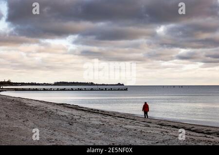 Insel Fehmarn, Deutschland. Januar 2021. Eine Frau geht unter dunklen Wolken am Südstrand. Kredit: Frank Molter/dpa/Alamy Live Nachrichten Stockfoto