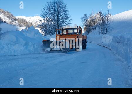 Orange Schneepflug LKW mit Schneeketten in einem gestoppt Ländliche verschneite Straße Stockfoto