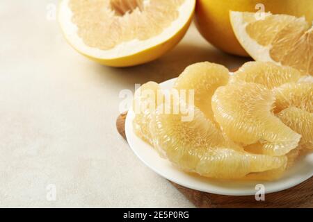 Reife Pomelo und Teller mit Pomelo Scheiben auf weiß strukturiert Hintergrund Stockfoto