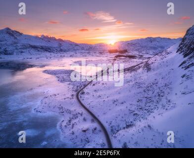 Luftaufnahme der kurvenreichen Straße, schneebedeckte Berge bei Sonnenuntergang Stockfoto