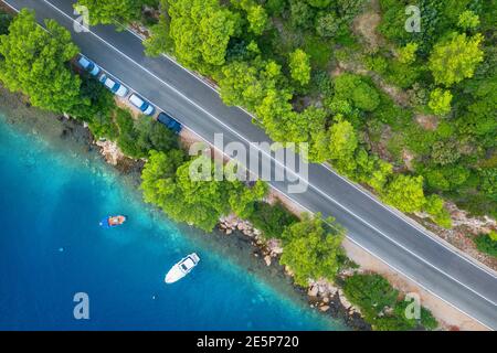 Blick auf die Straße im schönen grünen Wald und Meer im Frühling Stockfoto