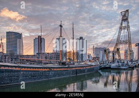 Rotterdam, Niederlande, 13. Januar 2021: Spektakulärer Himmel bei Sonnenaufgang über dem Hafen von Leuvehaven mit historischen Lastkähne und maritimer Ausrüstung Stockfoto