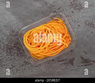 Draufsicht auf einen Plastikbehälter mit Butternut-Squash-Nudeln auf grauem Hintergrund. Stockfoto