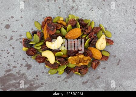 Draufsicht auf eine kleine Portion Samen, Nüsse und Früchte auf grauem Hintergrund. Stockfoto