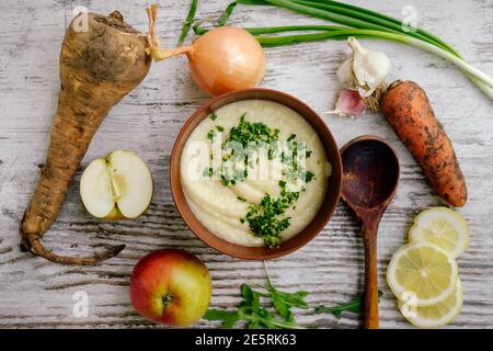 Pastinakensuppe mit Petersilie und Gemüse auf Holztisch, Draufsicht Stockfoto