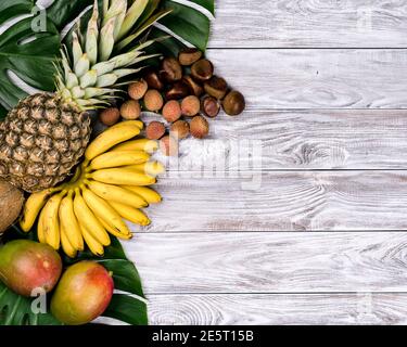 Frischen tropischen Früchten auf Holz Draufsicht. Bananen, Ananas, Kokos, Mango, Litschi Kastanien Stockfoto