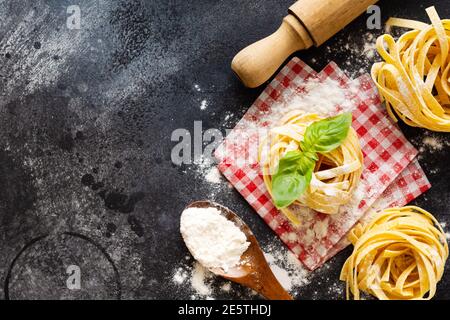Kochkonzept. Zutaten für traditionelle italienische hausgemachte Pasta-Tomaten, rohes Ei, Basilikumblatt auf dem dunklen Beton-Hintergrundtisch. Draufsicht mit Stockfoto
