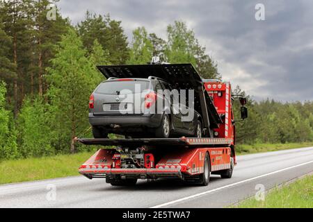 Renault Flachbett Recovery Vehicle von Ostermans ALLTRANS ab Oy trägt beschädigte Auto entlang der Autobahn an bewölktem Tag. Raasepori, Finnland. 24.Mai 2019. Stockfoto