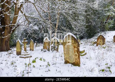 Friedhof und Grabsteine in St. John's Church in der Nähe von Woking, Diözese Guildford, Surrey, Südostengland nach einem starken Schneefall im Winter Stockfoto