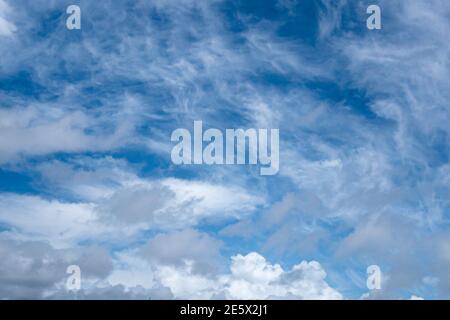Weiße und graue Wolken bilden abstrakte Muster im blauen Sommer Himmel Stockfoto