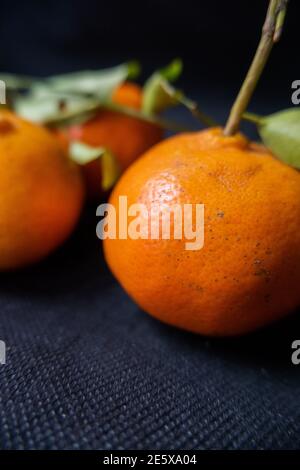 Mandarinen isoliert auf einem Tisch mit dunkler Tischdecke Stockfoto