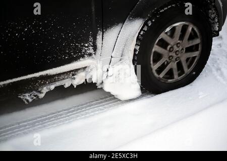 Der Schnee klebte auf einer Karosserie und einem Radbogen Fahren im Winter Stockfoto