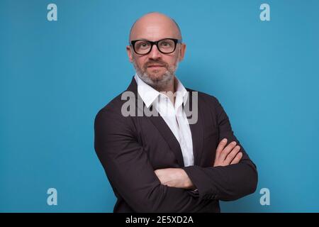 Schöner reifer Geschäftsmann im Anzug stehend mit gekreuzten Armen Blauer Hintergrund Stockfoto