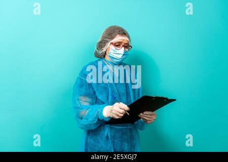 Stock Foto von nicht erkannten medizinischen Arbeiter tragen Schutzkleidung Notizen vor blauem Hintergrund. Stockfoto