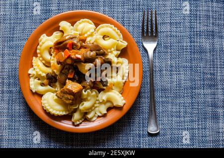 Traditionelle mediterrane Küche, italienisches Küchenkonzept. Servieren von verzehrfertigen Nudeln mit Soße, Eintöpfen, Pilzen und Gemüse auf Tonteller Stockfoto