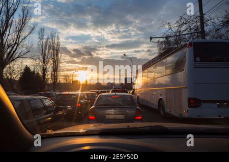 Stau am Abend bei Sonnenuntergang. Die Strahlen der Sonne machen ihren Weg durch die Wolken im Hintergrund. Stockfoto