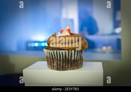 Nahaufnahme eines leckeren Schokoladen-Weihnachts-Cupcake mit einem kleinen Weihnachtsmann auf der Oberseite. Verschwommenes Manhattan New York City Lichter im Hintergrund Stockfoto