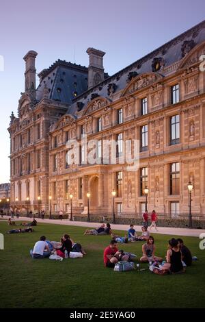 Menschen sitzen im Gras Museum und Bibliothek von dekorativen Kunst in der Nähe von Jardin des Tuileries und Louvers Stockfoto