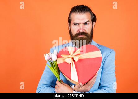 Ihre Bestellung ist fertig. Hochzeitstag. Happy valentines Tag. Braut Bräutigam mit Blumenstrauß und Box. Hipster Mann halten Tulpe Blumen. Liebe Geschenk für romantische Datum. Bärtiger Mann in eleganten Jacke halten Blumen. Stockfoto