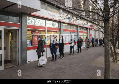 Schlange von Menschen, die sich außerhalb der Post, Abergavenny, Wales, Großbritannien, sozial distanzieren Stockfoto