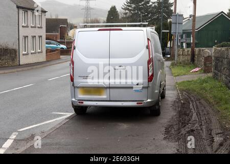 Fahrzeug auf dem Bürgersteig abgestellt, der den Fußweg behindert, zusammen mit Schlamm, der durch das Fahren am Rande entsteht, Wales, Großbritannien Stockfoto