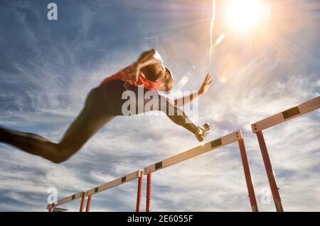 Läufer, die einen Sprung über die Hürde, niedrigen Winkel Ansicht ausführen Stockfoto