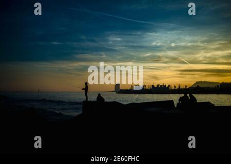 Barcelona, Spanien. Januar 2021. Pendler fischen an einem Wellenbrecher an Barcelonas Strandpromenade während des Sonnenuntergangs Quelle: Matthias Oesterle/Alamy Live News Stockfoto