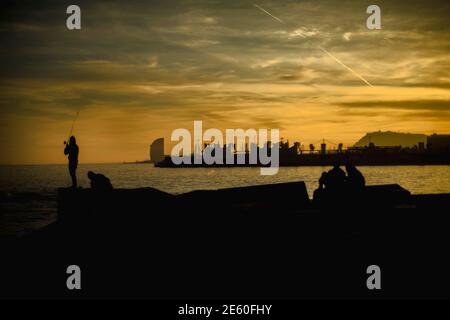 Barcelona, Spanien. Januar 2021. Pendler fischen an einem Wellenbrecher an Barcelonas Strandpromenade während des Sonnenuntergangs Quelle: Matthias Oesterle/Alamy Live News Stockfoto