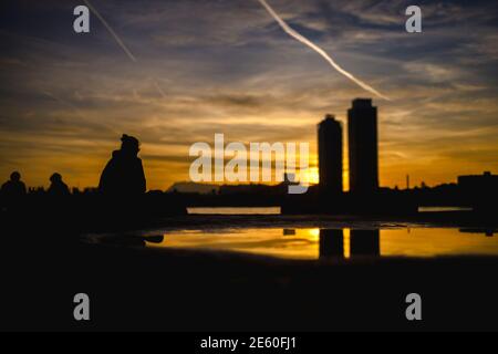 Barcelona, Spanien. Januar 2021. Pendler sitzen auf einem Wellenbrecher an Barcelonas Strandpromenade und betrachten einen Sonnenuntergang Quelle: Matthias Oesterle/Alamy Live News Stockfoto
