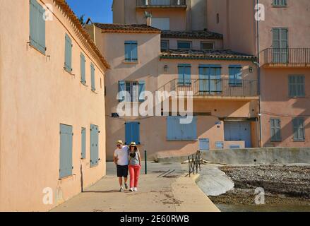 Junges Paar, das am Meer entlang der traditionellen ockerfarbenen Häuser in Saint-Tropez, Französische Riviera Provence Frankreich, geht. Stockfoto