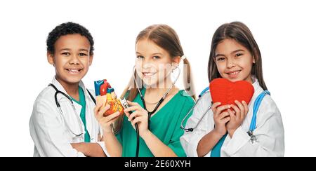 Gruppe positiver multiethnischer Kinder in medizinischen Uniformen und Stethoskopen. Medizinische Versorgung und Betreuung, Konzept des zukünftigen Arztberufs Stockfoto
