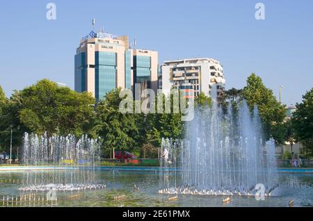 Tirana, Albanien - 21. Juli 2012: Der Brunnen im Rinia Park, dem zentralen öffentlichen Park von Tirana, auf dem Hintergrund einige Wolkenkratzer; der Wolkenkratzer auf dem Stockfoto