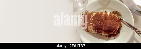 Banner mit traditionellen italienischen Tiramisu mit Schokolade auf der Oberseite, als Dessert serviert, mit Copy-Platz für Text auf angenehmen glatten Hintergrund Stockfoto