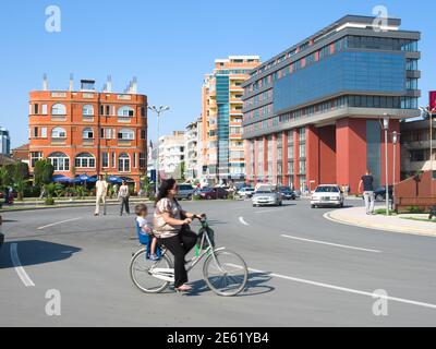 Shkoder, Albanien - 31. Juli 2012: Bewegung für eine Frau auf einem Fahrrad, das sein Kind auf einem Rücksitz auf dem Democracy Square im Zentrum von Shko bringt Stockfoto