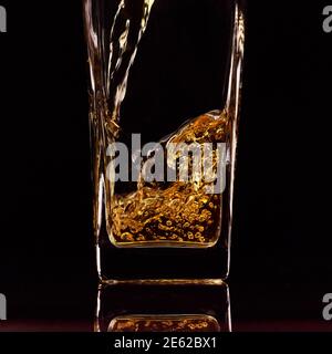 Nahaufnahme des Gießen von frischem Apfelsaft in das Glas. Schwarzer Hintergrund. Zeitlupe. Gesunde Lebensmittel, Vitamine, Früchte Stockfoto