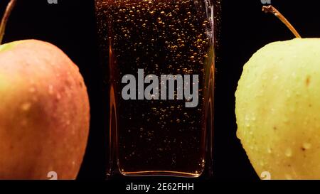 Nahaufnahme von Gießen von frischem Apfelsaft in Glas und grünen Äpfeln vor schwarzem Hintergrund. Gesunde Lebensmittel, Vitamine, Früchte Stockfoto