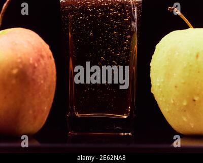 Nahaufnahme von Gießen von frischem Apfelsaft in Glas und grünen Äpfeln vor schwarzem Hintergrund. Gesunde Lebensmittel, Vitamine, Früchte Stockfoto