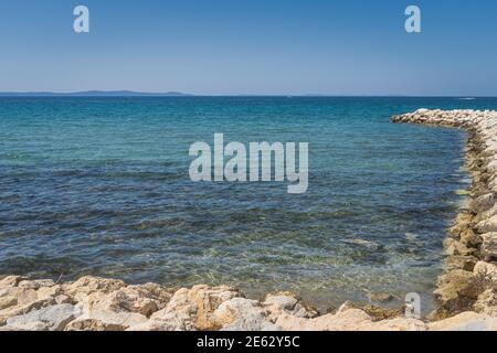 Ruhiges, türkisfarbenes und kristallklares Wasser der Adria mit felsigen Pier in der Bucht von Zaton, Kroatien Stockfoto