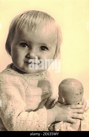 ZWICKAU, OSTDEUTSCHLAND - UM 1970s: Das Retro-Foto zeigt, dass das Mädchen einen Dolly hält. Studio-Foto. Schwarzweiß-Foto.1970s Stockfoto