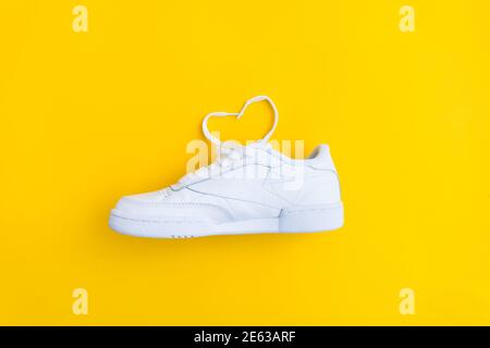 Liebe zum Sport-Konzept mit weiblichen stylischen weißen Casual Sneakers Auf gelb Stockfoto