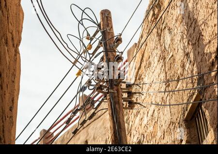 Elektrische Kabel auf der hölzernen Stromsäule im alten Bergdorf Misfat Al Abriyeen im Sultanat von Oman. Stockfoto