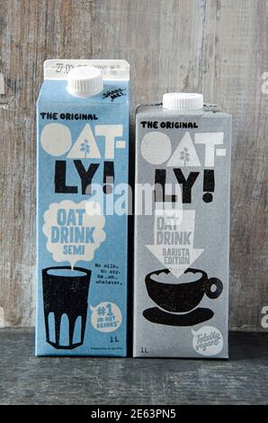Zwei Kartons mit Oatly veganer Hafermilch oder -Getränk; die Original Oatly Semi und die Barista Edition vor Holzhintergrund Stockfoto