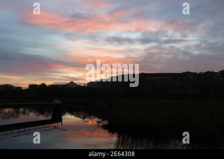 Blick in der Morgendämmerung über die Teiche und Schilfbeete im öffentlichen Park Las Llamas von Atlantic Sardinero Santander Cantabria Spanien spiegelte den orangefarbenen Himmel wider Stockfoto