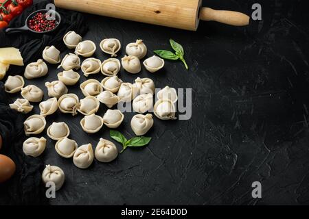 Italienische Tortellini mit frischen Ricotta-Blättern und Tomaten Set, auf schwarzem Hintergrund, mit Copyspace und Platz für Text Stockfoto