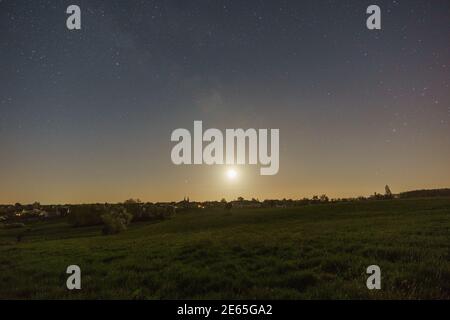 mond und Milchstraße über Wiese mit Bäumen außerhalb eines deutschen Dorf in der eifel Stockfoto