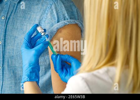 Der Arzt wählt den Impfstoff in eine Spritze. Eine Krankenschwester mit einem Impfstoff und einer Spritze in den Händen Stockfoto