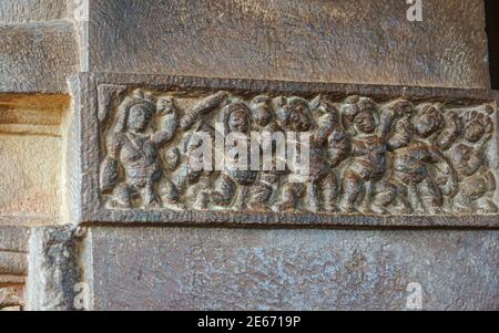 Aihole, Karnataka, Indien - 7. November 2013: Durga Gudi oder Tempel. Graue Steinreihe oder Linie von menschlichen Figuren Fresko. Stockfoto