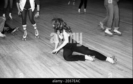 Skater versuchen, eine Frau zu vermeiden, die auf einer Rollschuhbahn in Los Angeles, CA um die 1970er Jahre gefallen ist Stockfoto