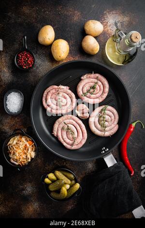 Bayerische Bratwurst auf Sauerkraut in gusseiserner Bratpfanne, auf altem dunklen rustikalen Hintergrund, Draufsicht Flachlage Stockfoto