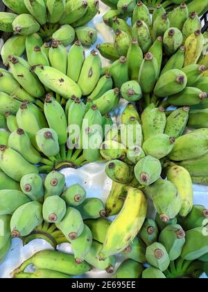 Grüne Bananen sind noch roh auf dem Stand zum Verkauf Auf dem Markt Stockfoto